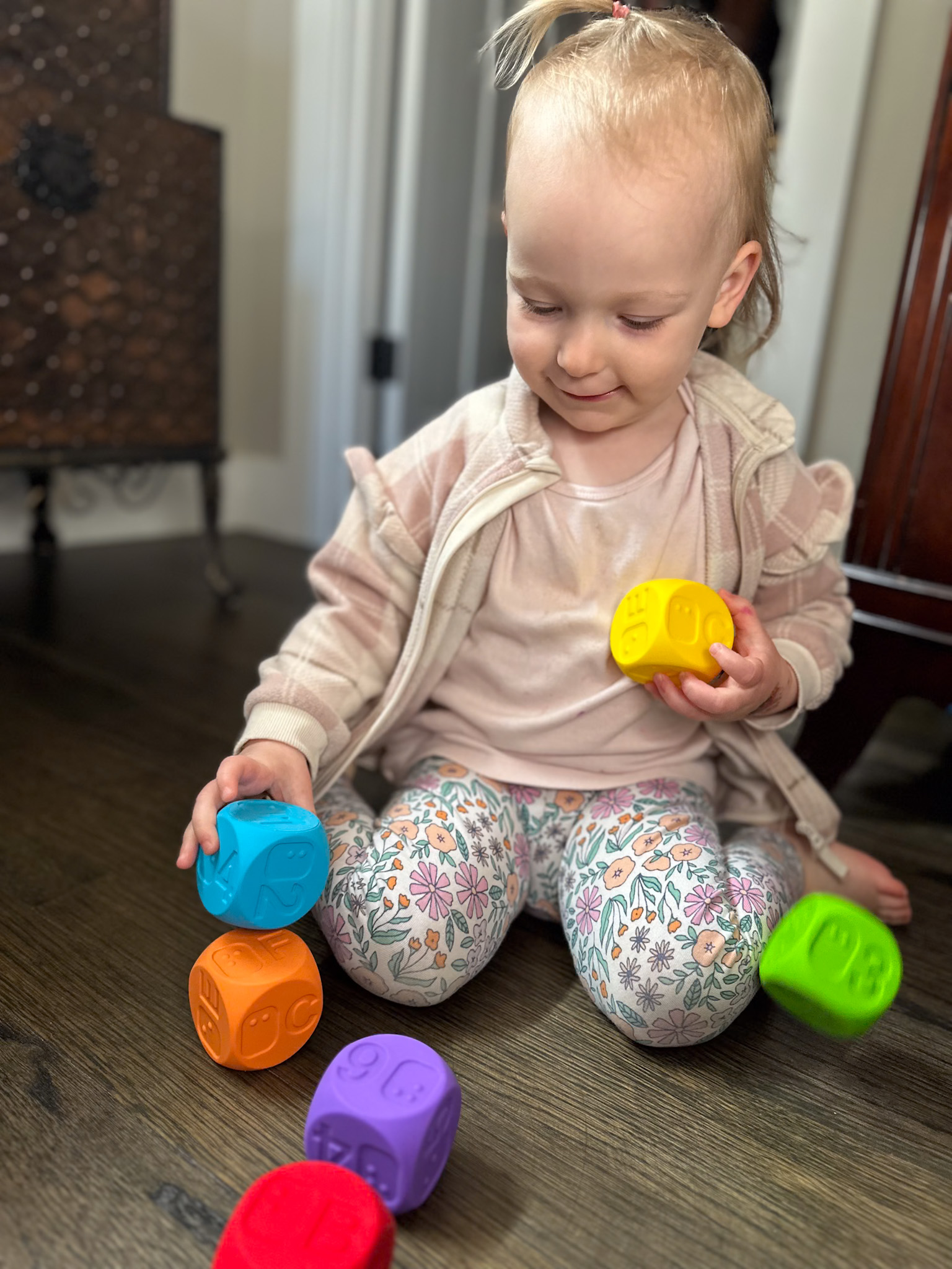 A young toddler playing with the print and braille rainbow blocks